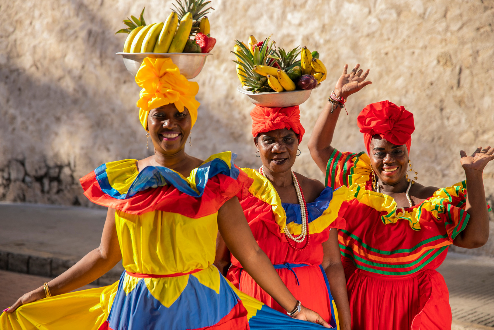 Women in Bright Colorful Dresses with Fruit Bowls on Head